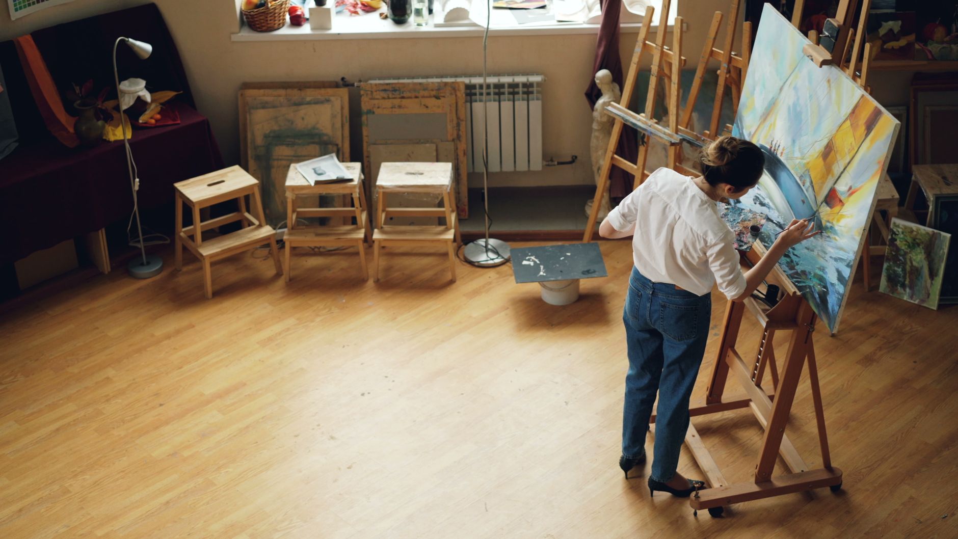 Illustrator Lena Park painting at her studio table surrounded by brushes
