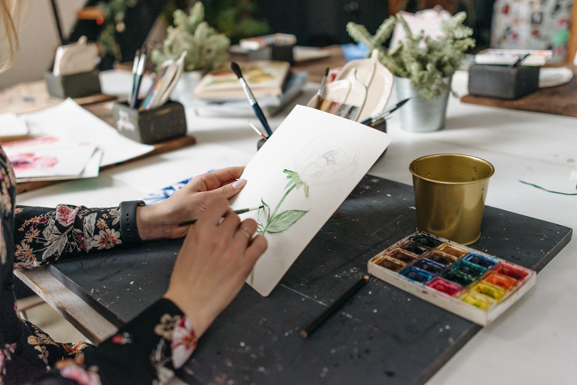 Student painting with watercolours at a sunlit desk